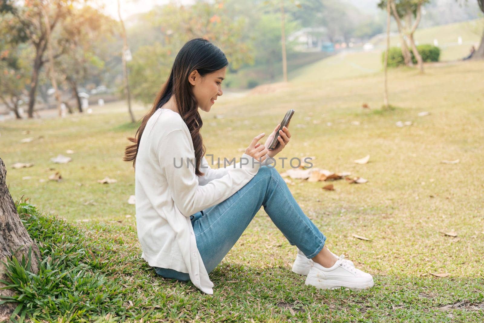 young smiling woman in on in park outdoors rest use mobile cell phone see news online. People urban lifestyle concept.