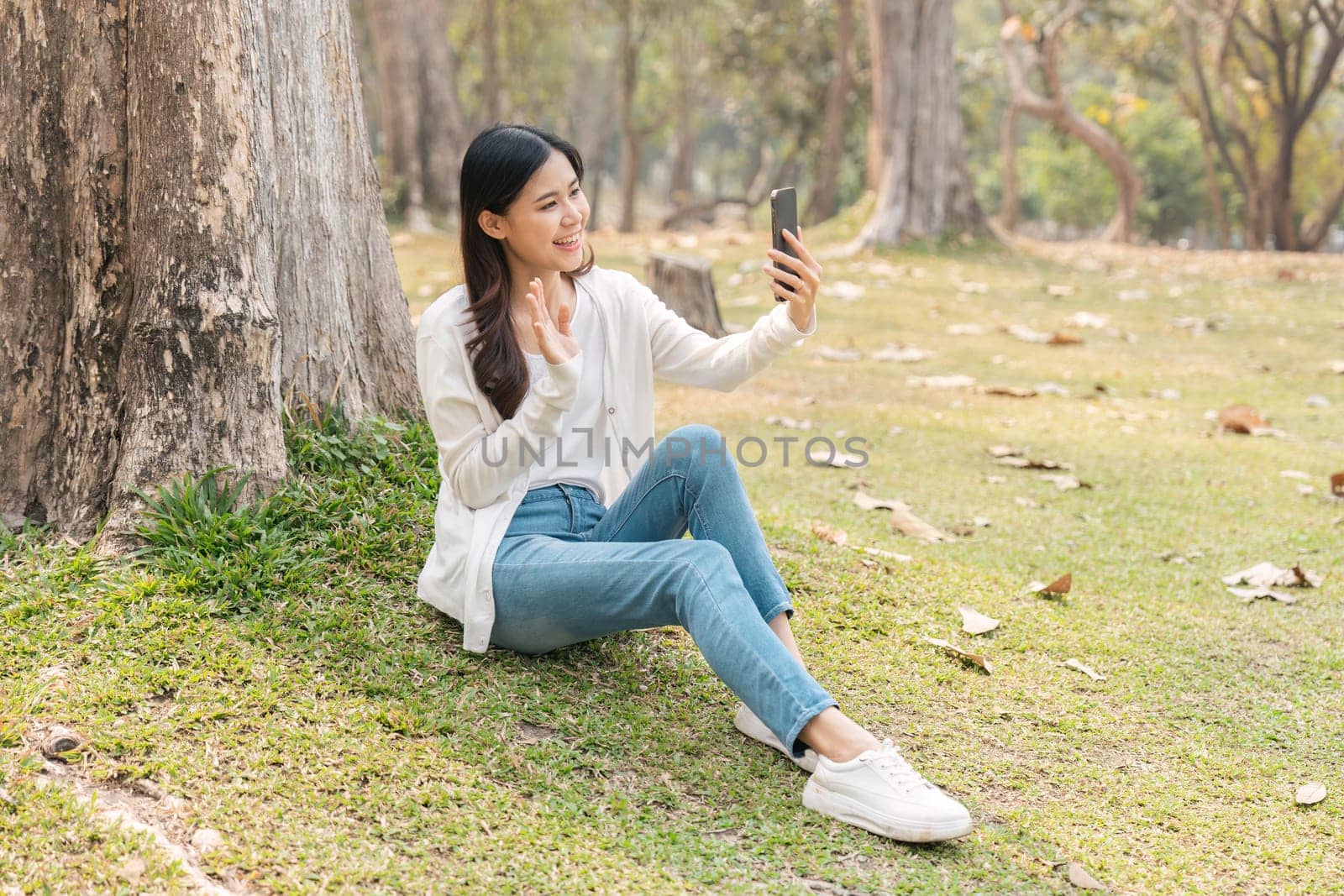 young woman in on in park rest use mobile cell phone video call to family or friends.