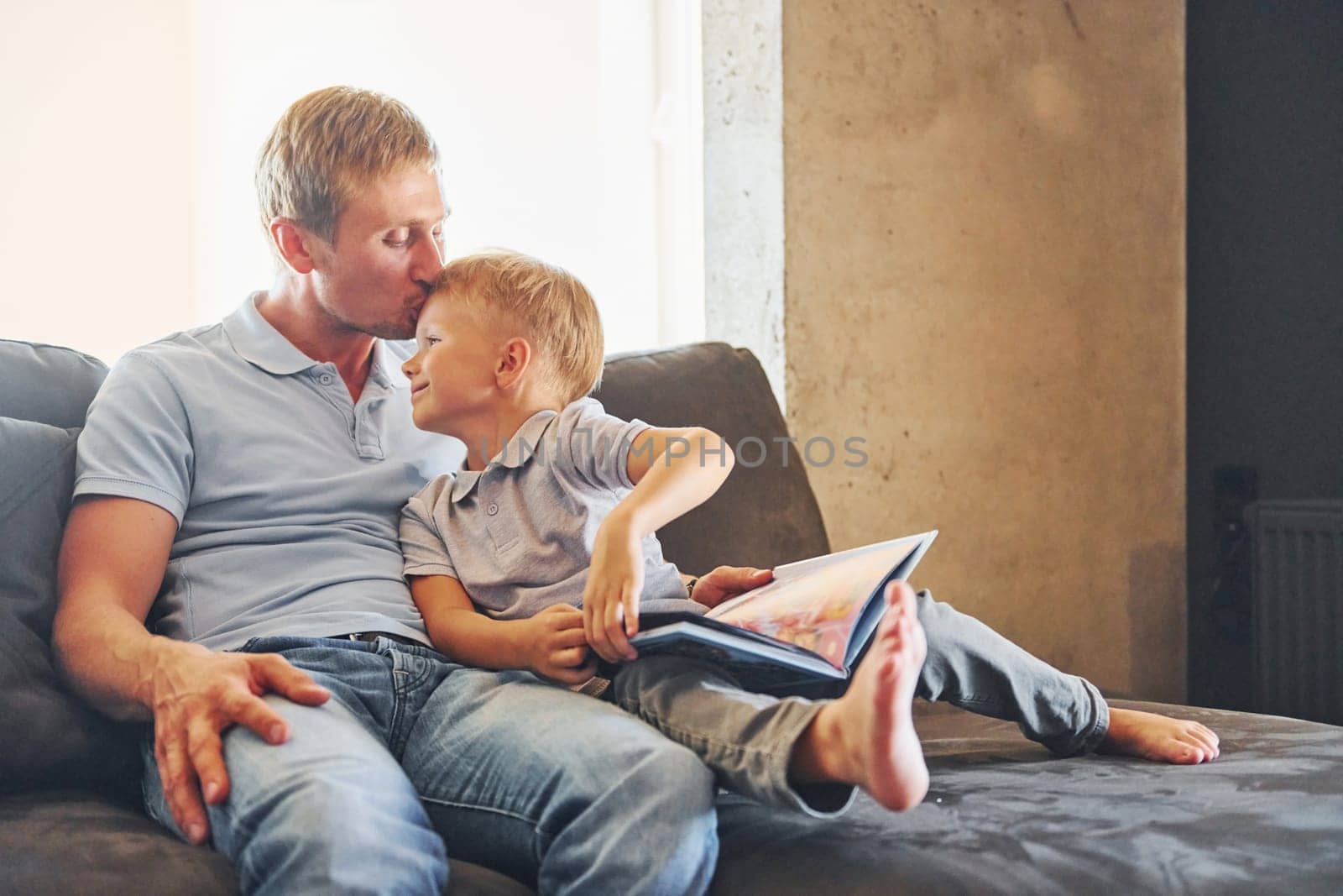 Sitting on the sofa. Father and son is indoors at home together.