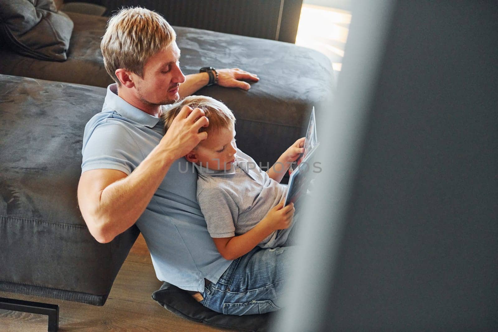 Having free time. Father and son is indoors at home together.
