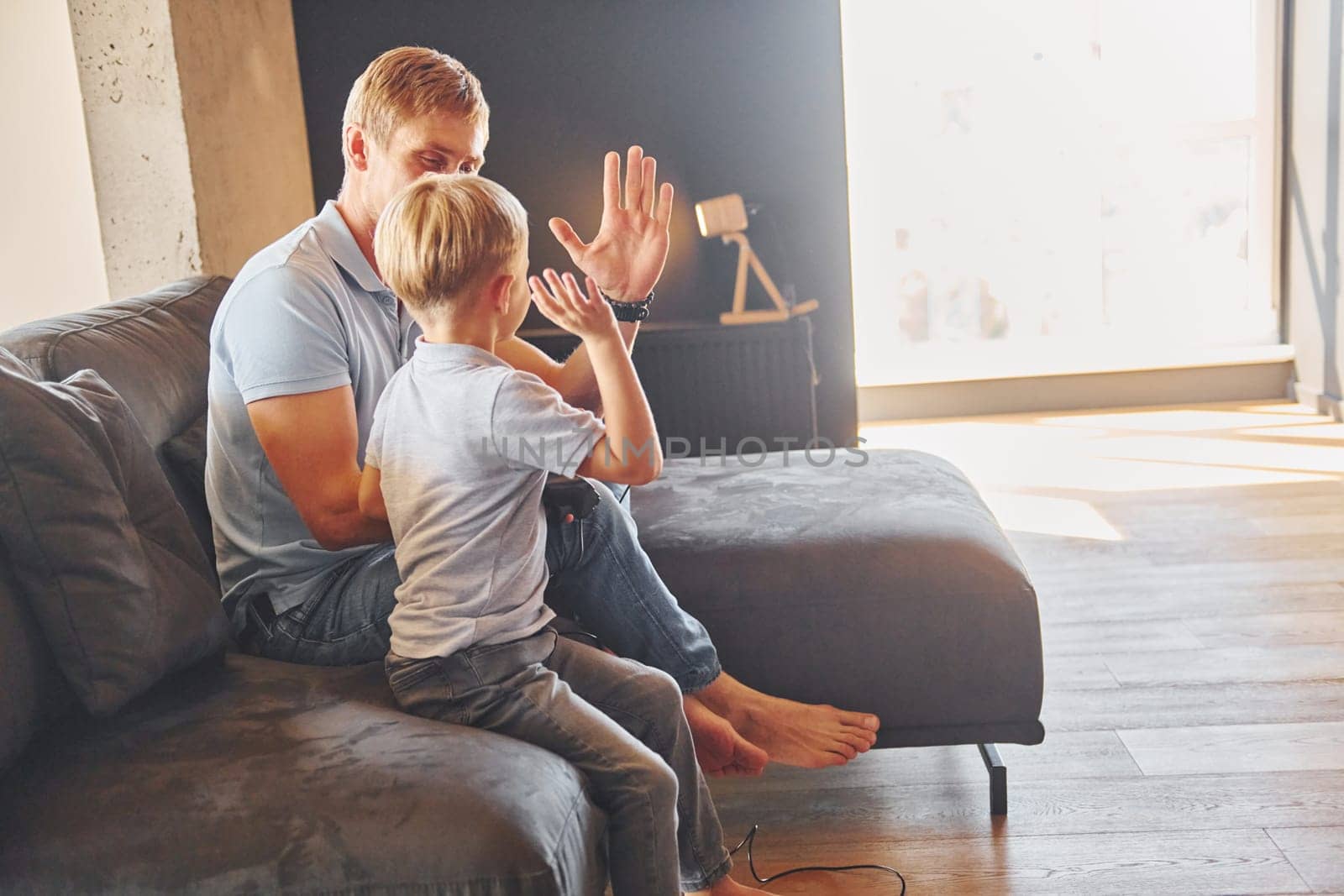 Playing video game. Father and son is indoors at home together.