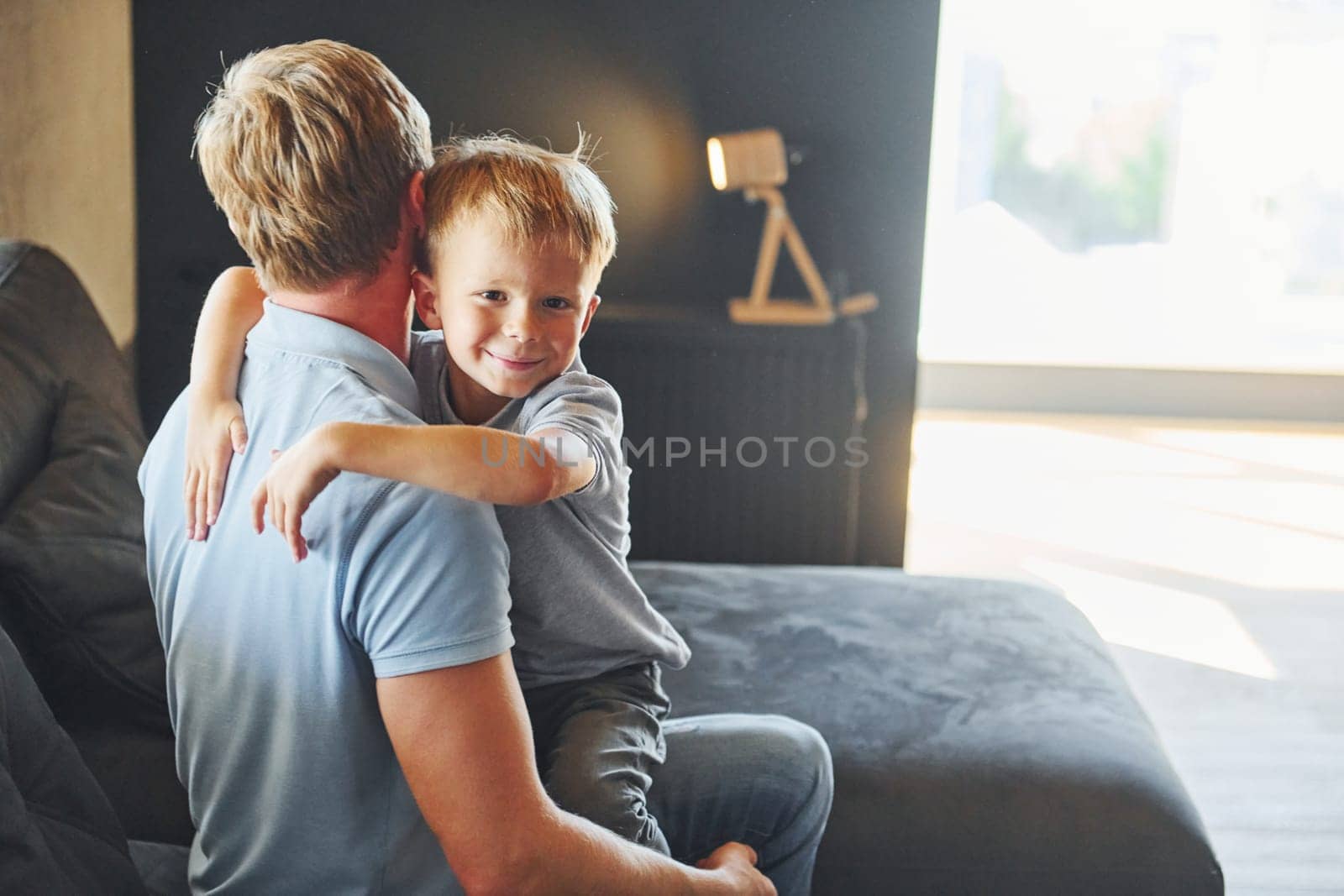 Boy embracing his parent. Father and son is indoors at home together.