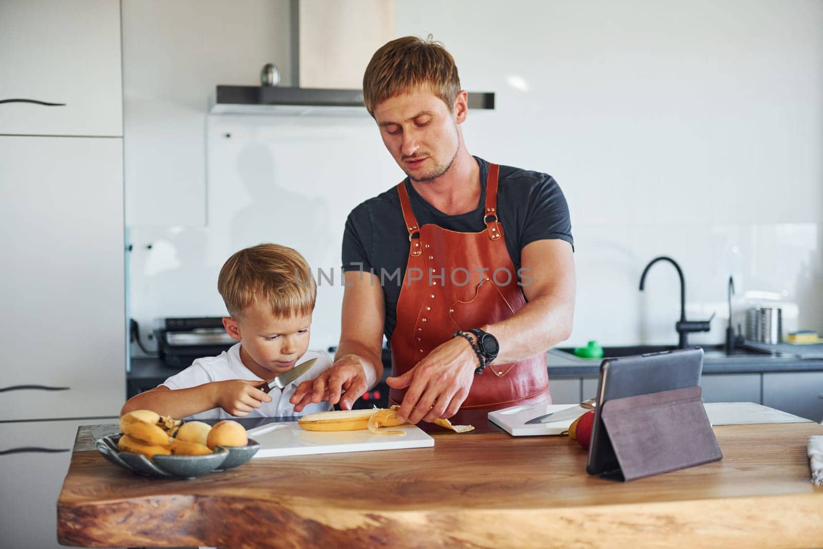 Learning how to cook. Father and son is indoors at home together.