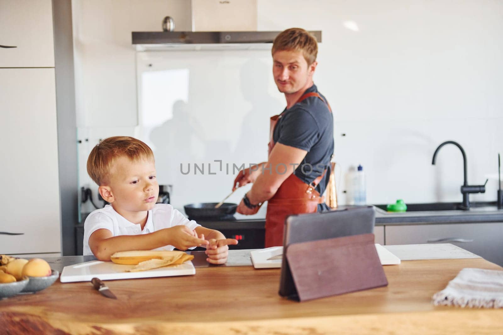 Using tablet to learn how to cook. Father and son is indoors at home together.