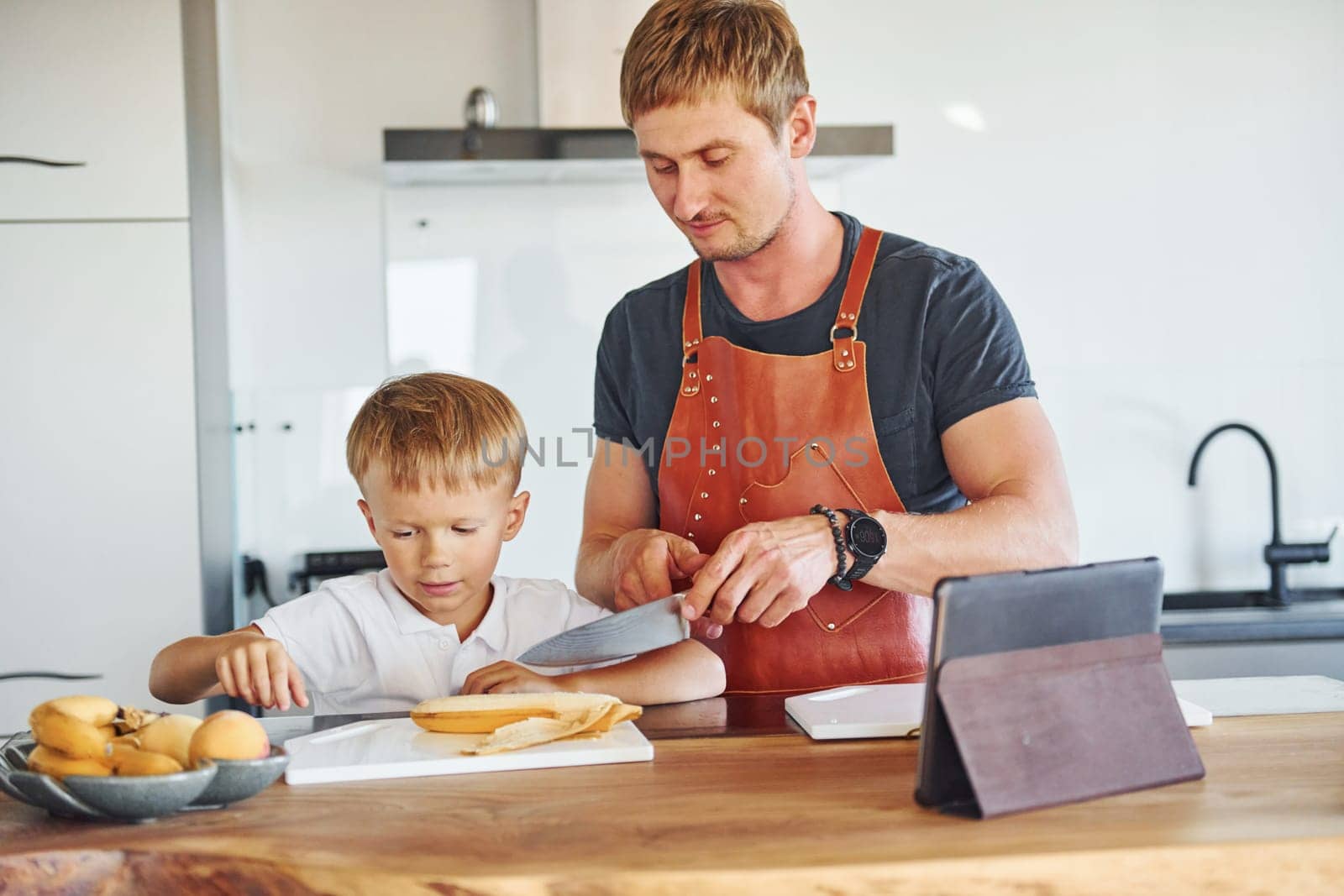 On the kitchen with food. Father and son is indoors at home together.