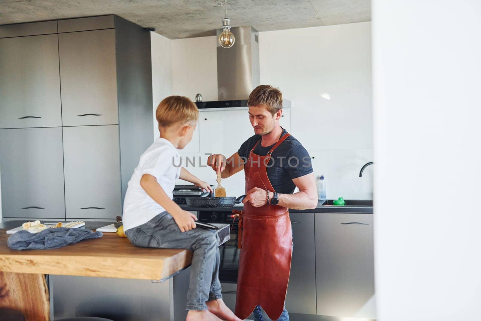 Preparing some food. Father and son is indoors at home together.