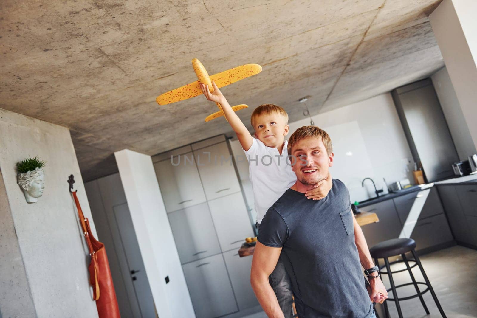 Yellow toy plane. Father and son is indoors at home together.