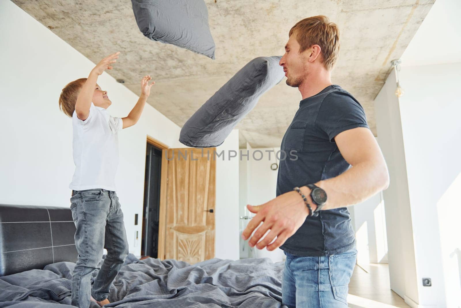 Pillow fight. Father and son is indoors at home together.