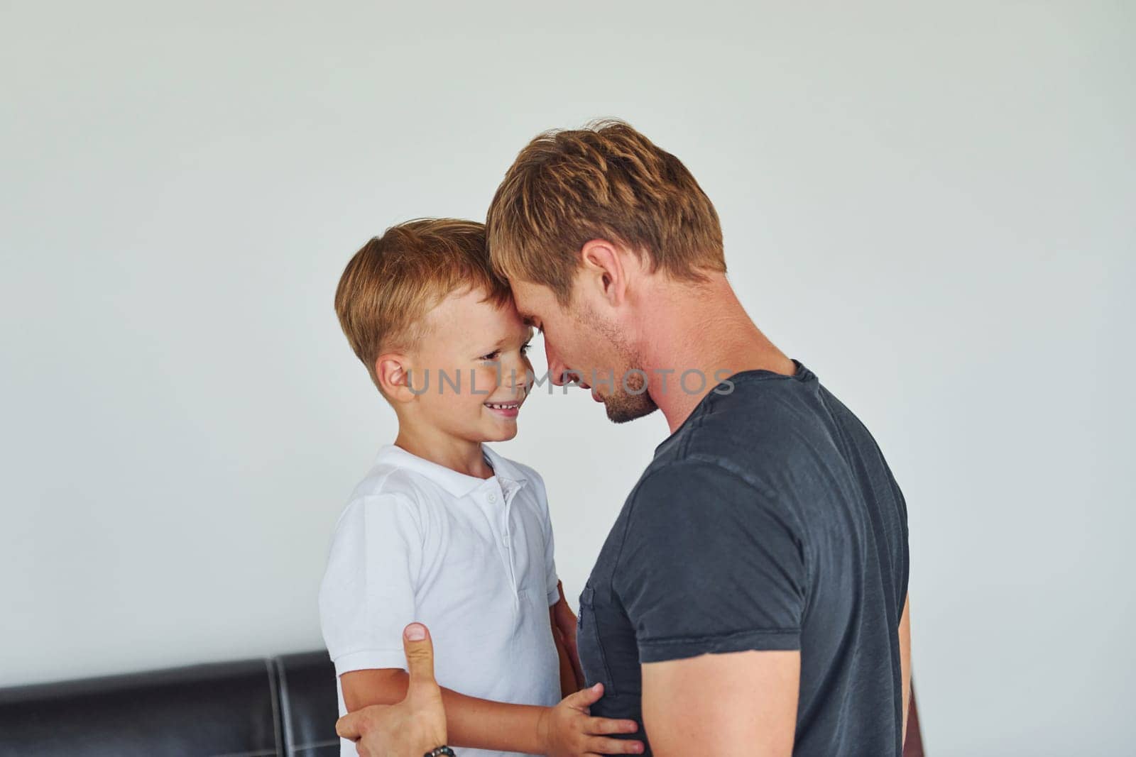 Embracing each other. Father and son is indoors at home together by Standret