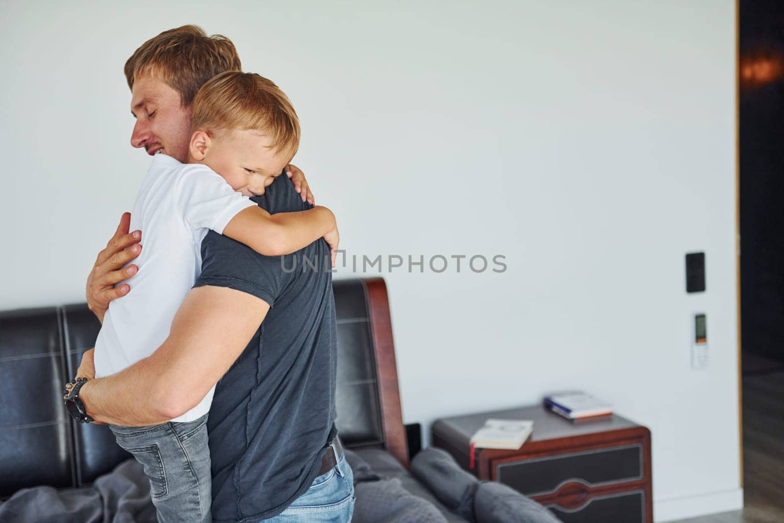 Embracing each other. Father and son is indoors at home together.