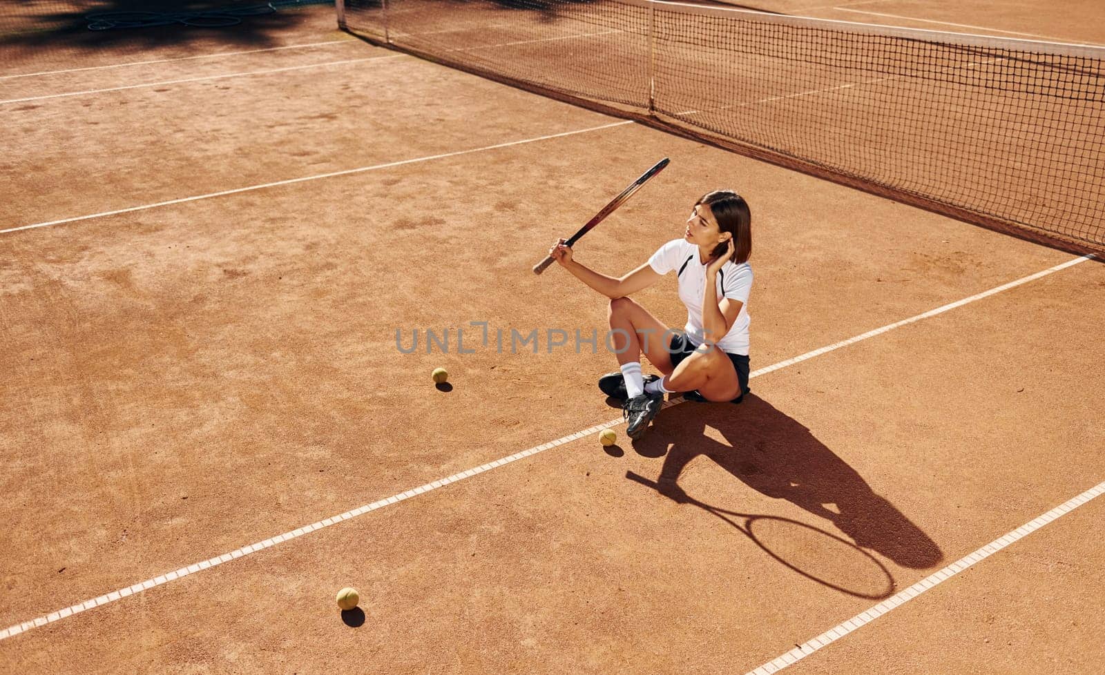 Near the net. Female tennis player is on the court at daytime.