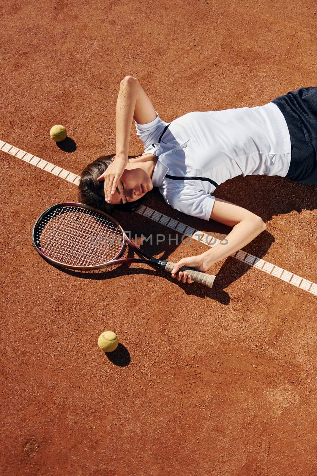 View from above. Female tennis player is on the court at daytime.