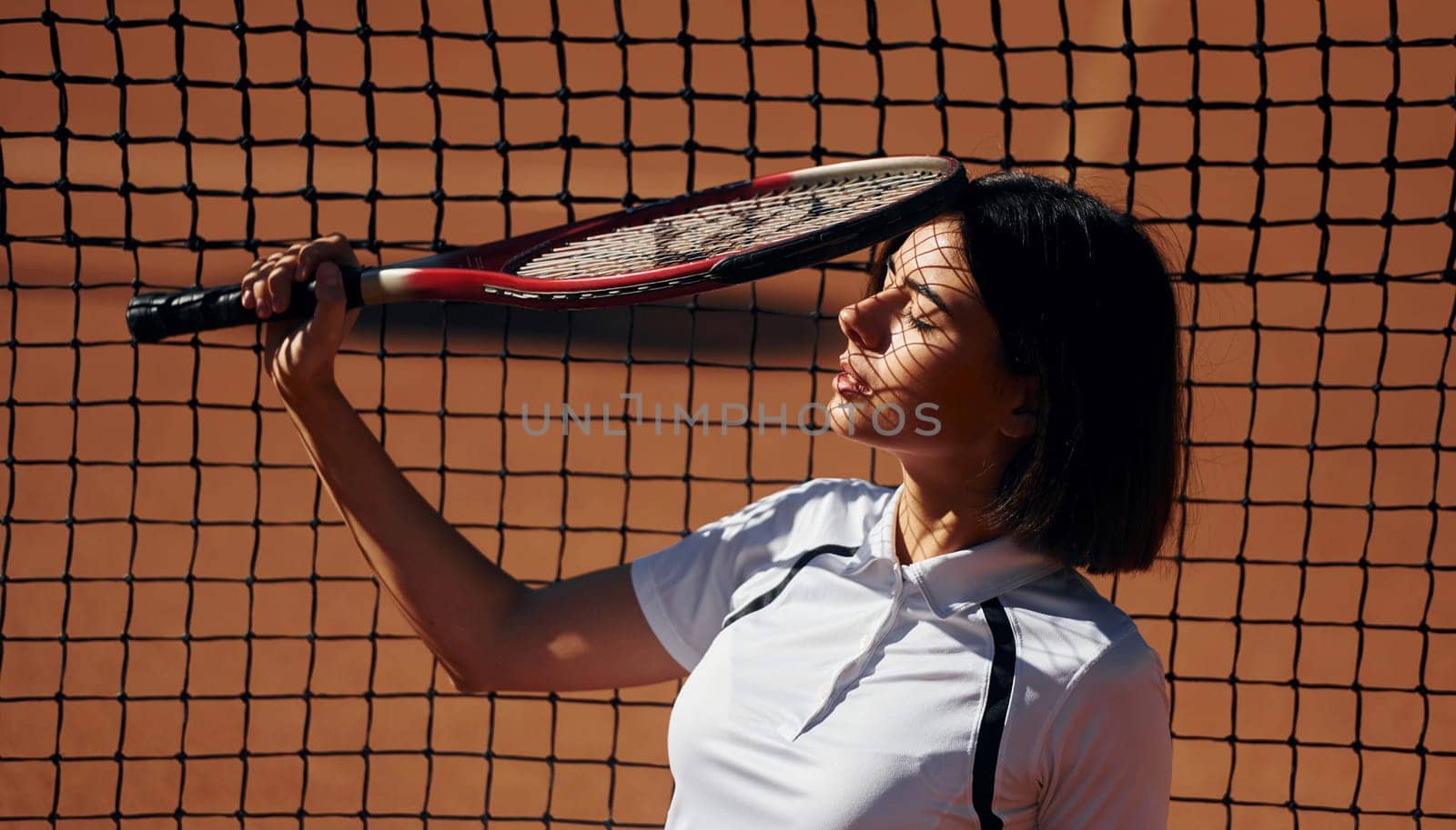 Having a break. Female tennis player is on the court at daytime.