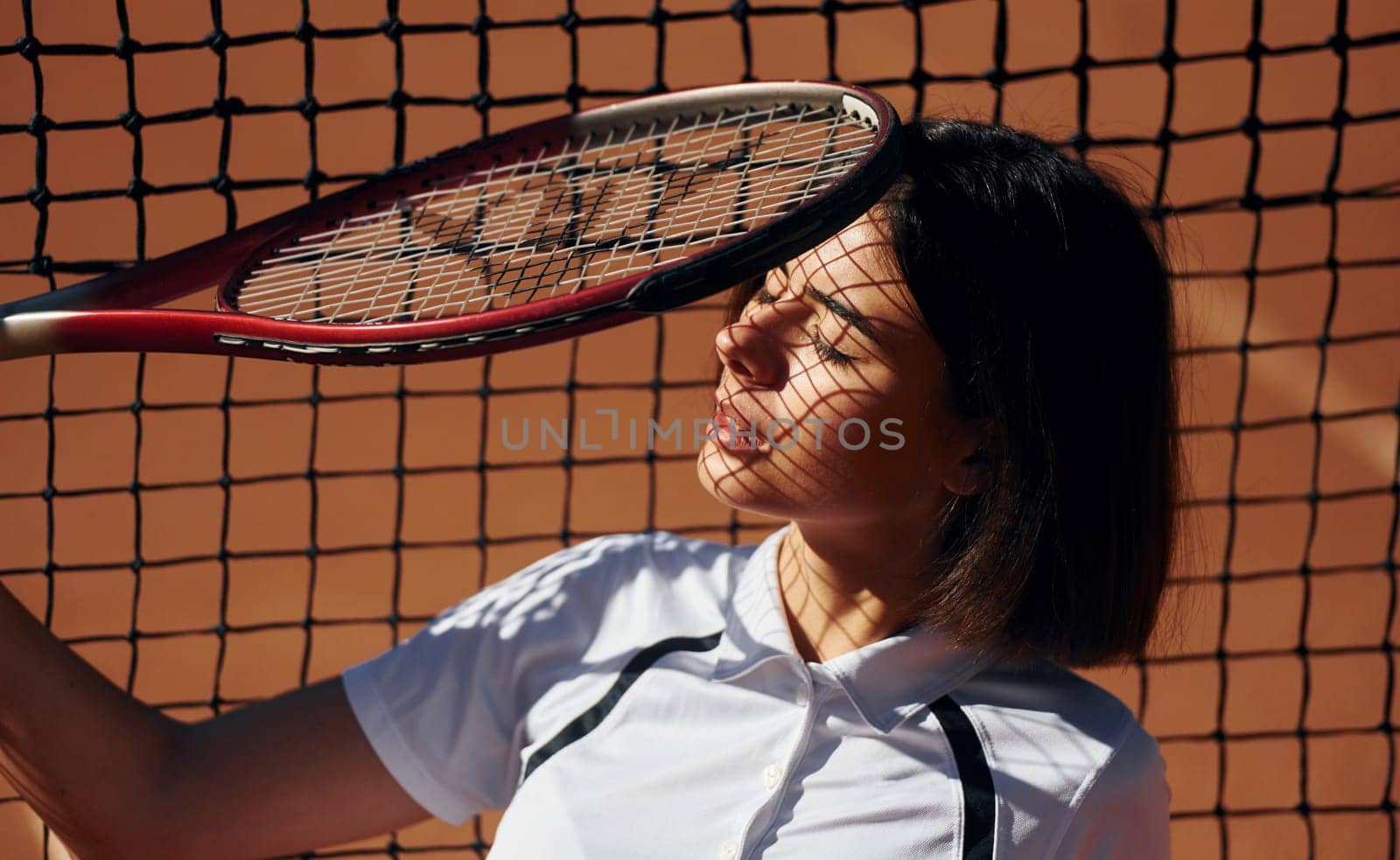 Having a break. Female tennis player is on the court at daytime.