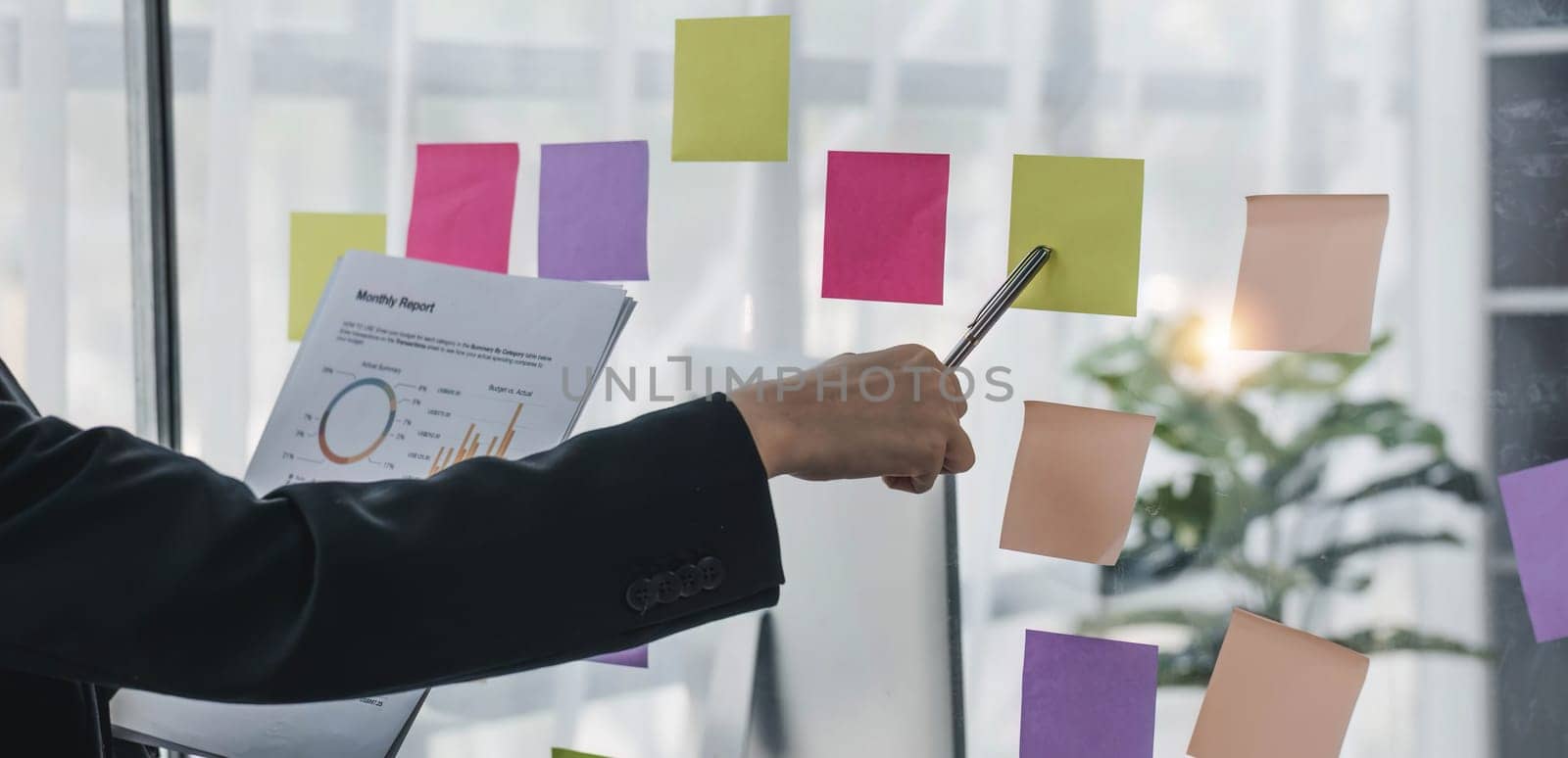 Young businesswoman creative team using post it notes in glass wall to writing strategy business plan to development grow to success...