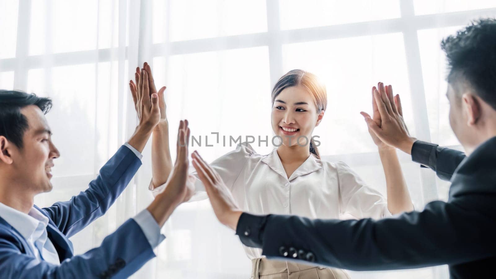 Business Team Achievement Success Mission Concept. Happy successful business team giving a high fives gesture as they laugh and cheer their success by wichayada