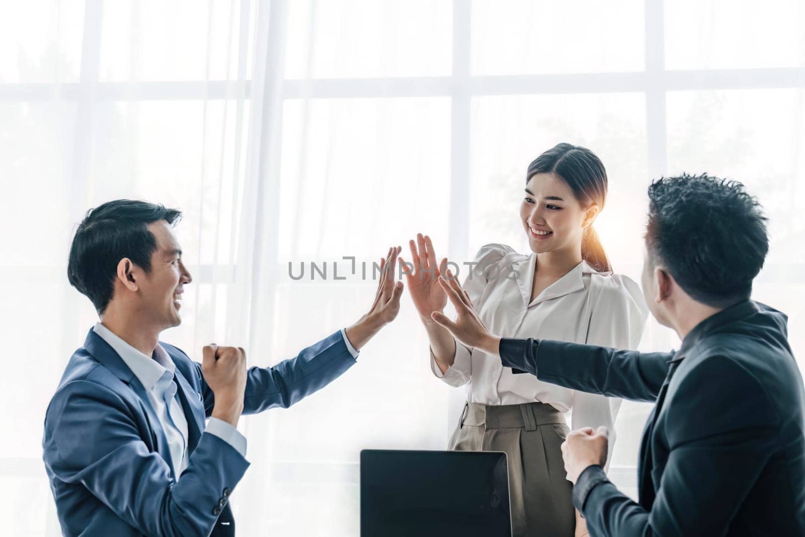 Business Team Achievement Success Mission Concept. Happy successful business team giving a high fives gesture as they laugh and cheer their success..