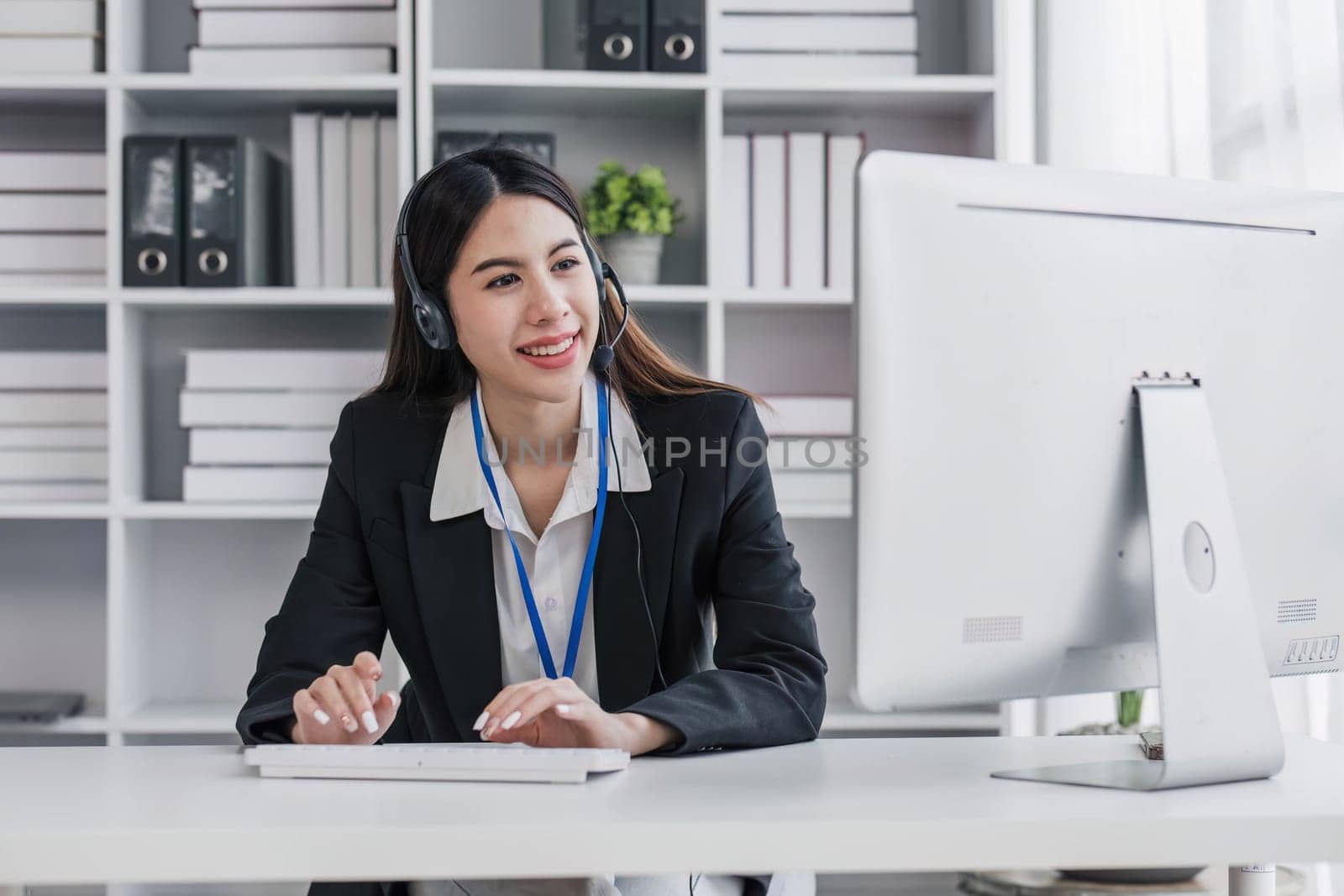 close up call center operator in wireless headset talking with customer, woman in headphones with microphone consulting client on phone in customer support service, looking at computer screen...