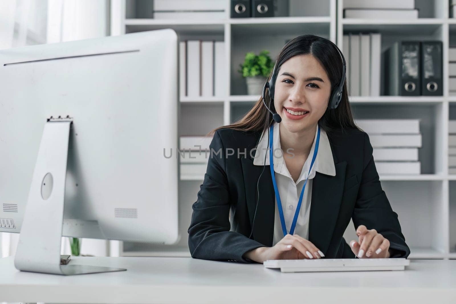 close up call center operator in wireless headset talking with customer, woman in headphones with microphone consulting client on phone in customer support service, looking at computer screen...