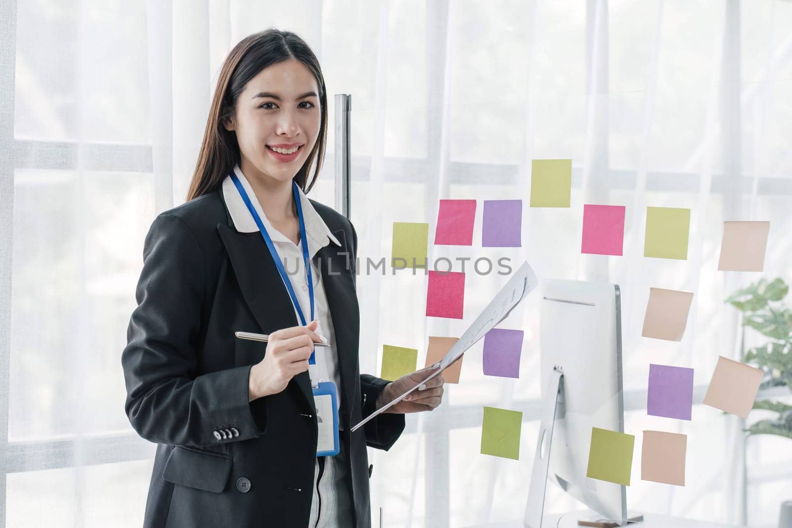 Young businesswoman creative team using post it notes in glass wall to writing strategy business plan to development grow to success...