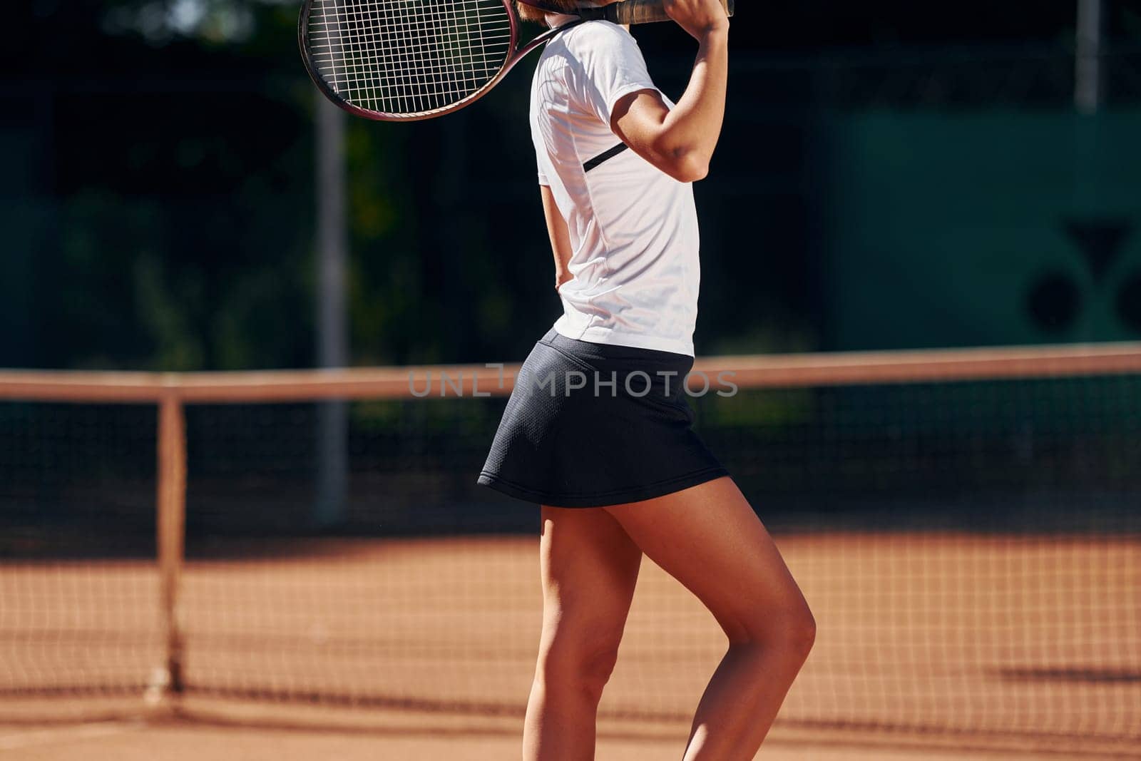 Female tennis player is on the court at daytime posing for a camera.