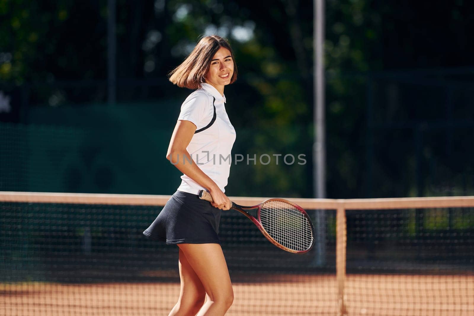 Female tennis player is on the court at daytime.