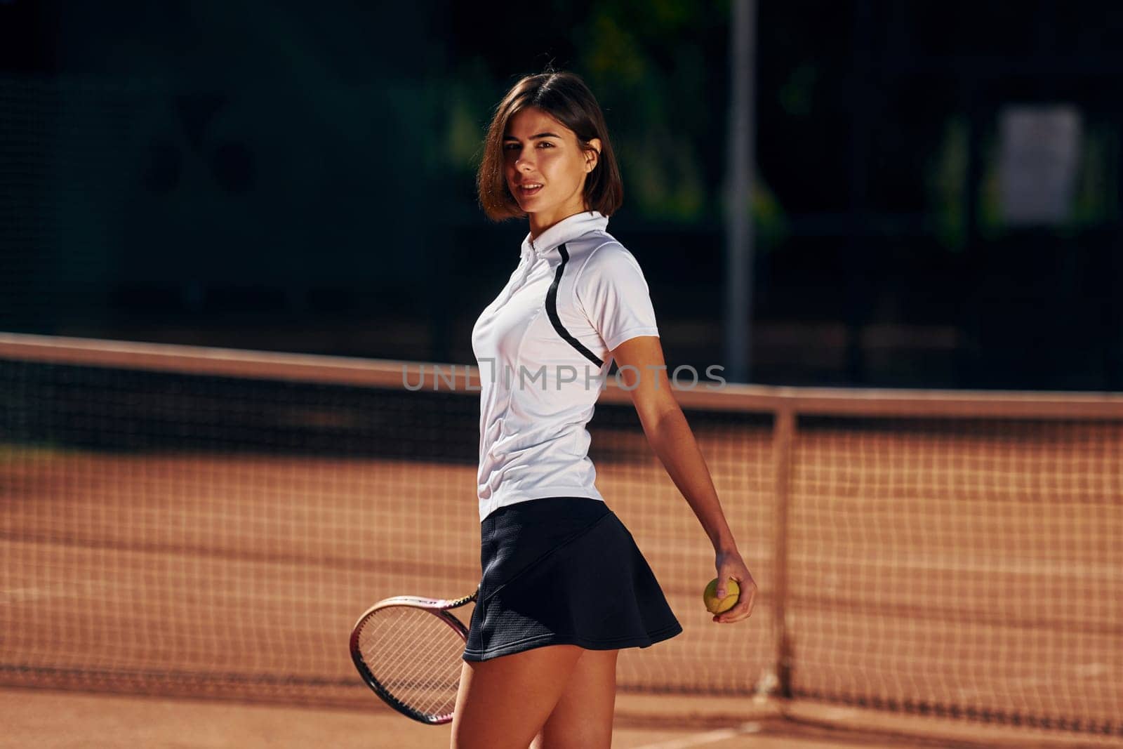 Female tennis player is on the court at daytime.