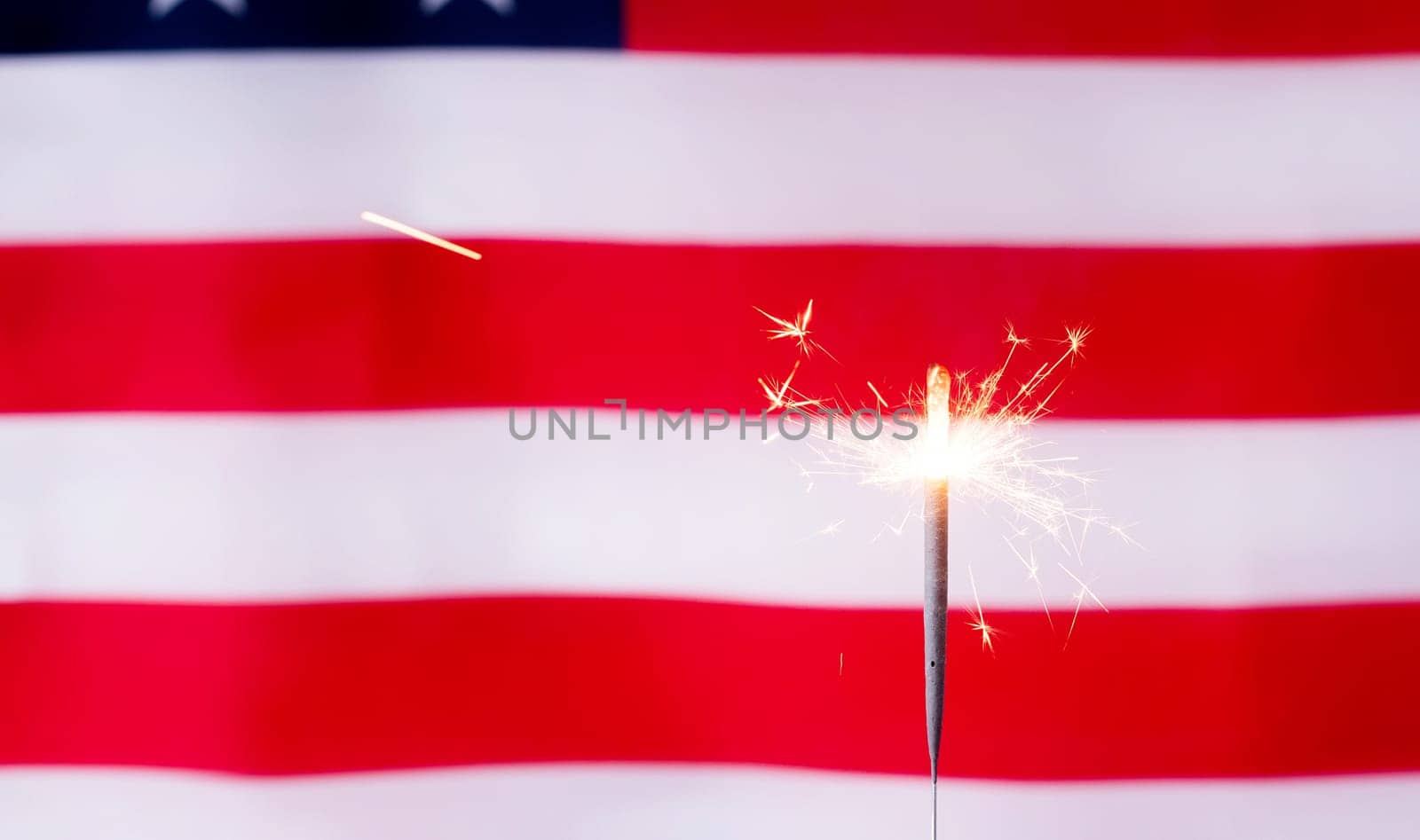 Fourth of july celebration.Shining sparkler over USA flag background