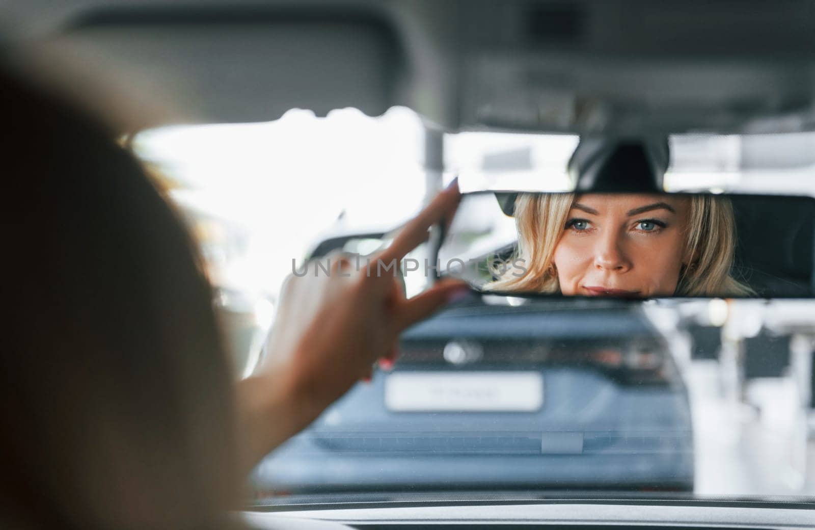 In the car. Woman in formal clothes is indoors in the autosalon.
