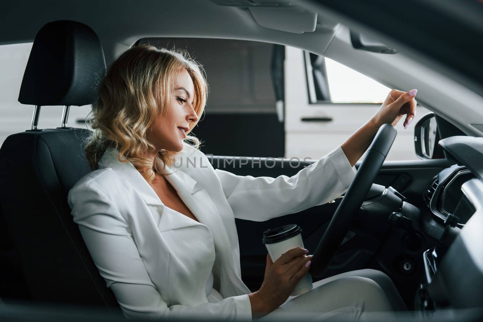 In the car. Woman in formal clothes is indoors in the autosalon.