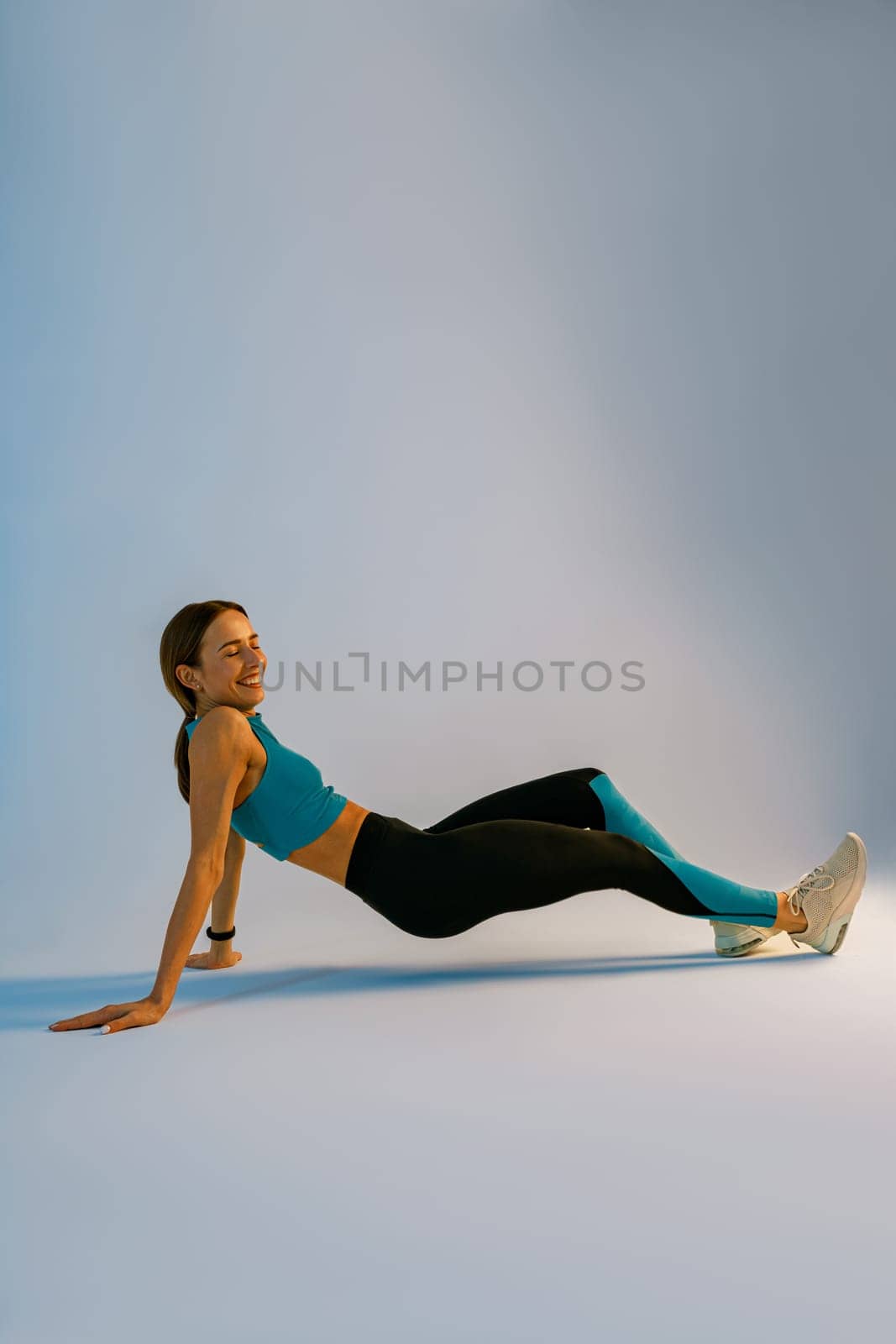 Smiling Fit Woman standing in plank position on studio background. Healthy Lifestyle Concept by Yaroslav_astakhov