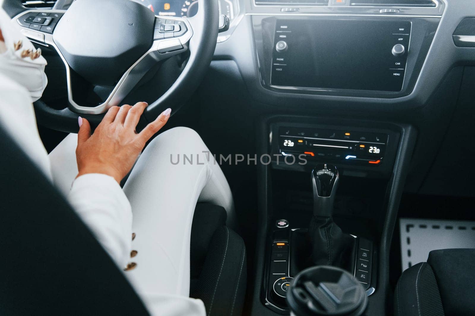 Vehicle interior. Woman in formal clothes is indoors in the autosalon.