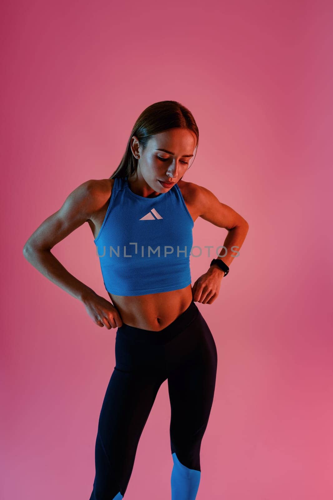 Beautiful fitness woman wearing sportswear posing over studio background and looking at side by Yaroslav_astakhov
