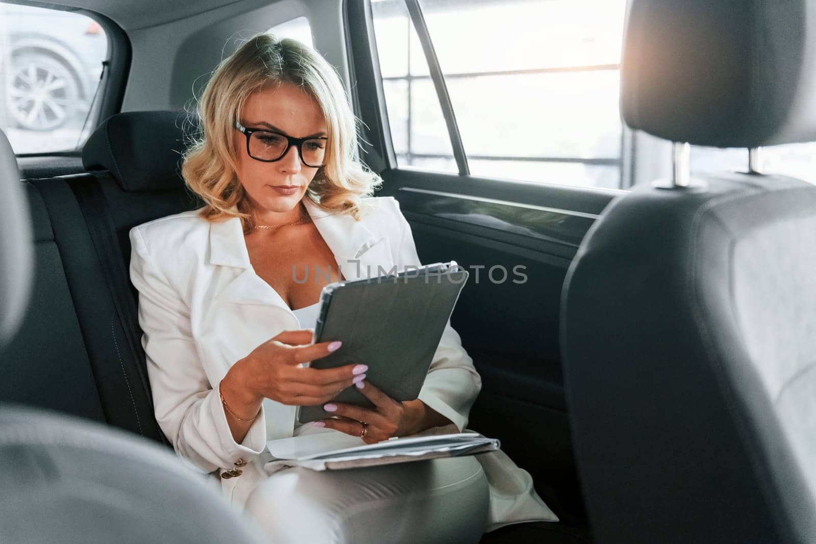 Working in the car. Woman in formal clothes is indoors in the autosalon.