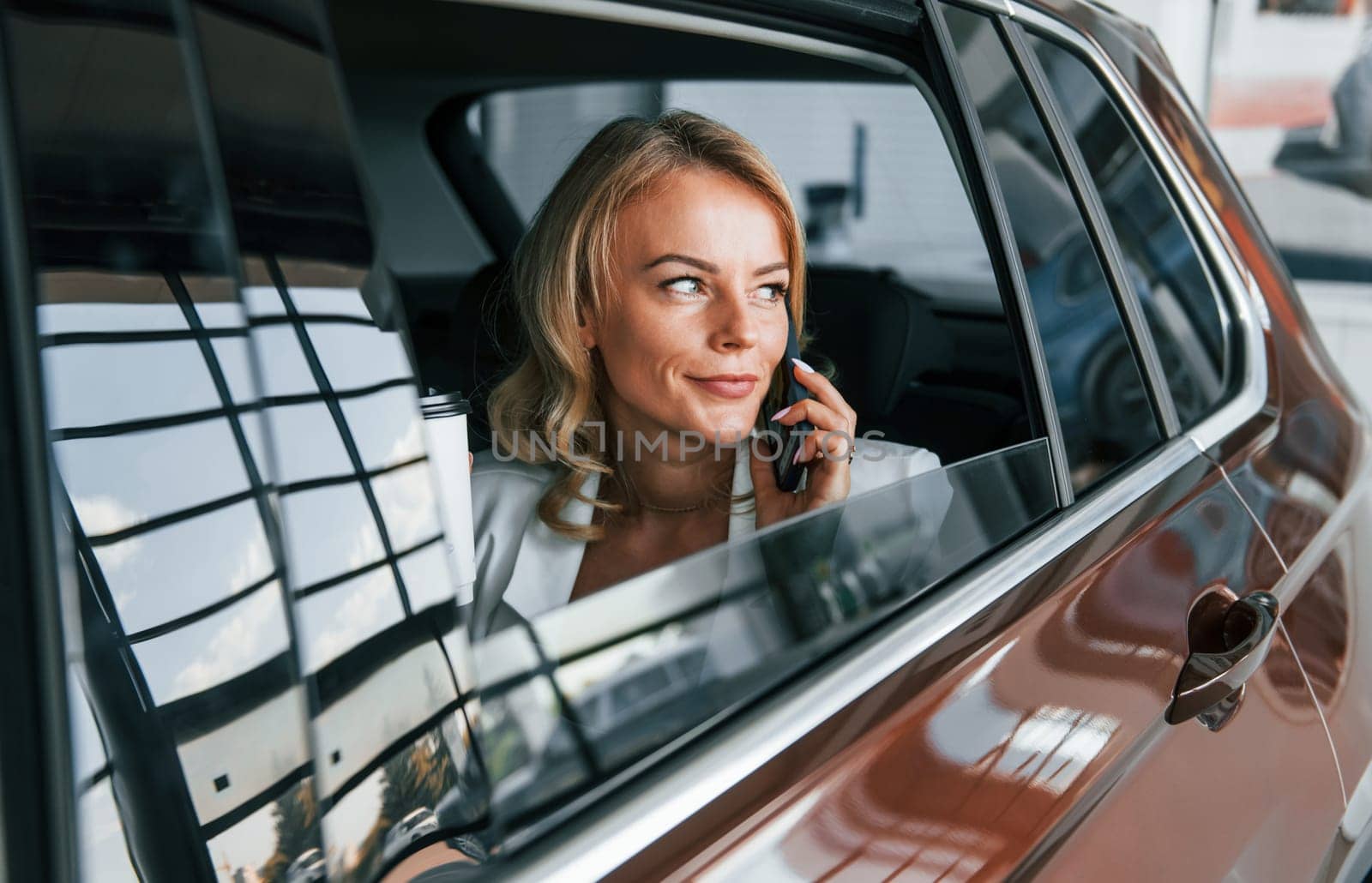 Side view. Woman in formal clothes is indoors in the autosalon.