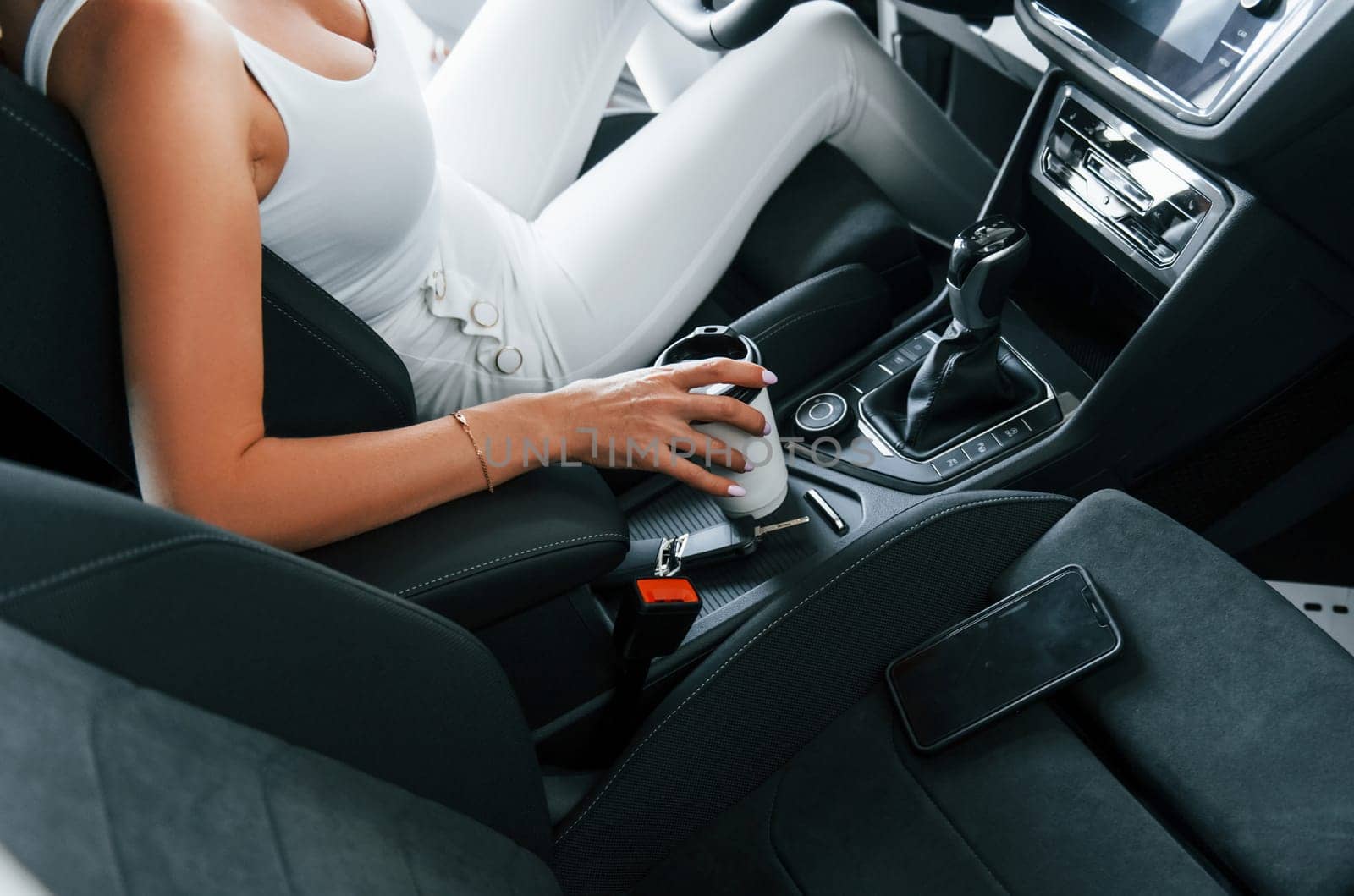 Comfortable car. Woman in formal clothes is indoors in the autosalon.