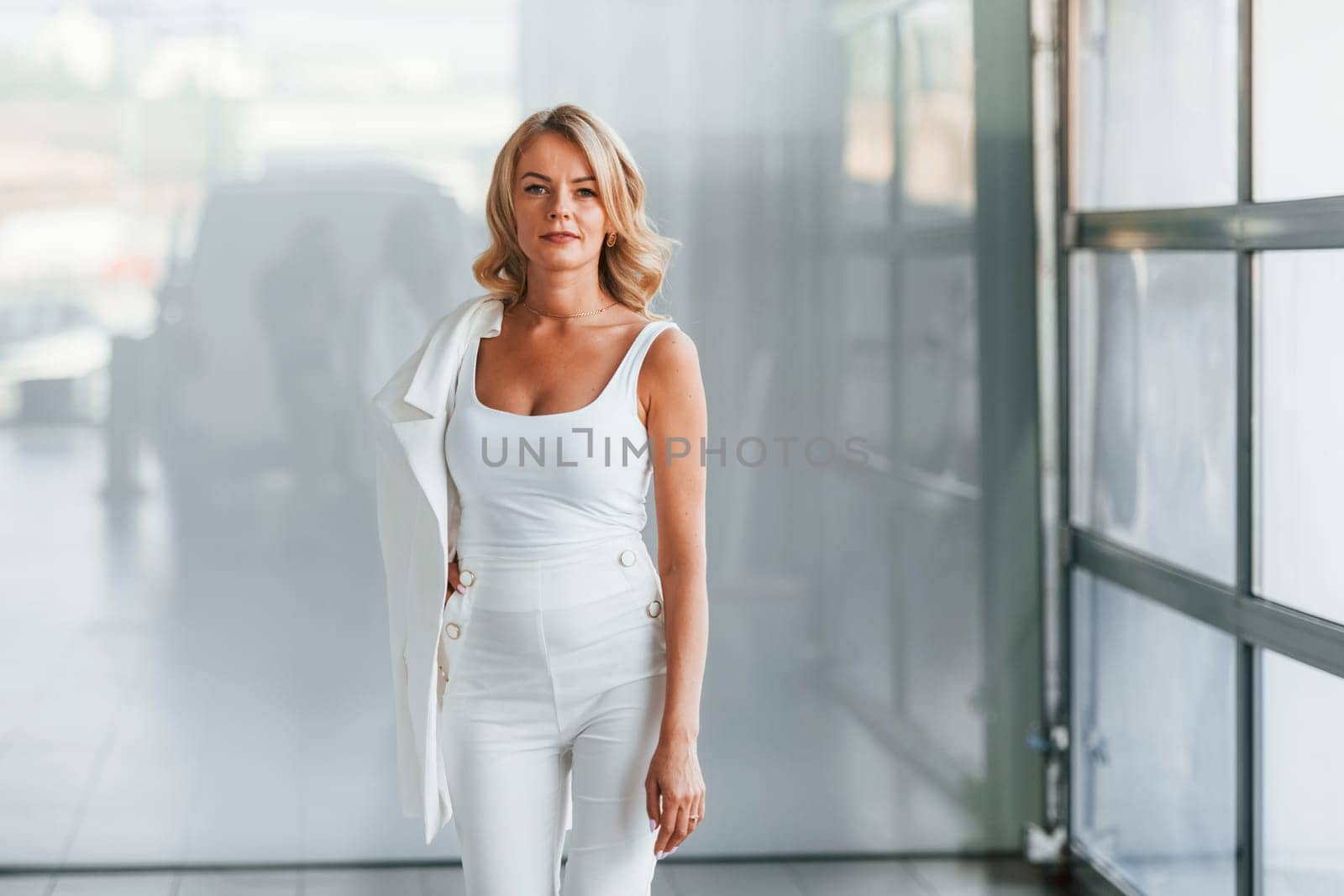 Posing for the camera. Woman in formal clothes is indoors in the autosalon.