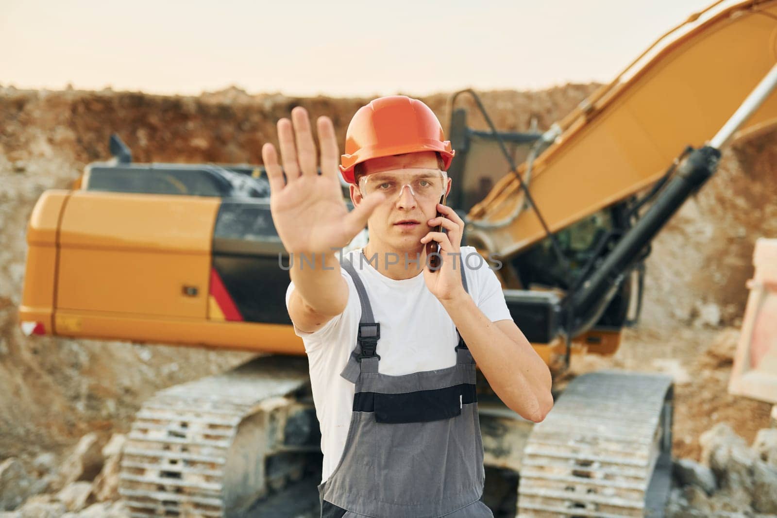 Portrait of worker in professional uniform that is on the borrow pit at daytime.