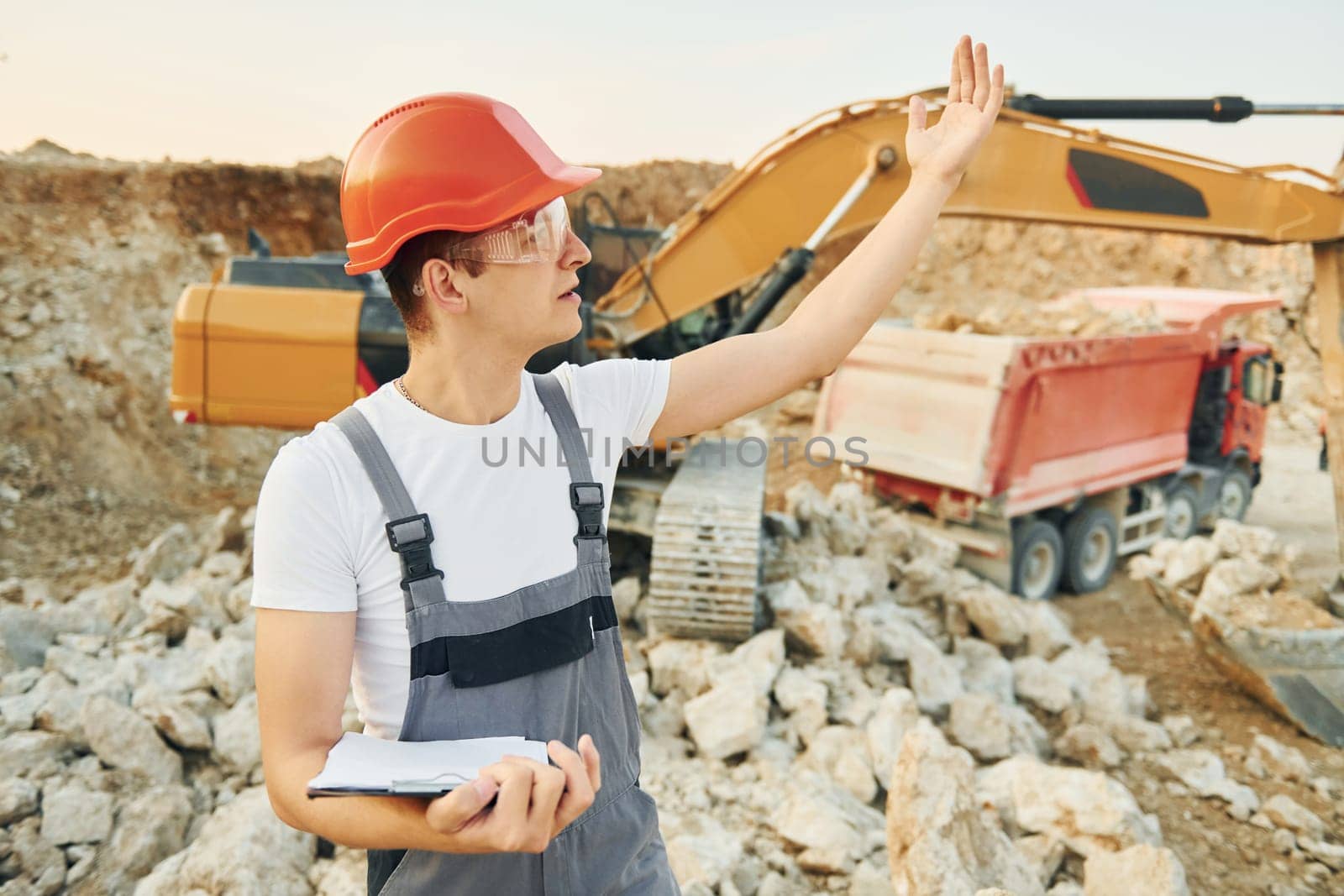 Restricted area. Worker in professional uniform is on the borrow pit at daytime.