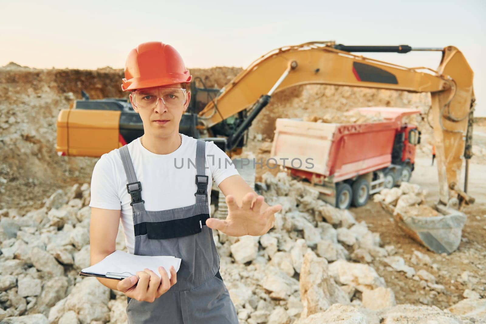 Restricted area. Worker in professional uniform is on the borrow pit at daytime.