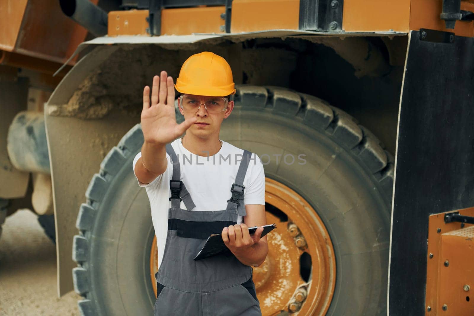 Manager planning the work. Man in professional uniform is on the borrow pit at daytime.