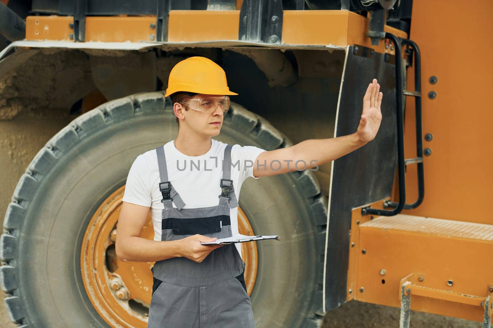 Manager planning the work. Man in professional uniform is on the borrow pit at daytime.