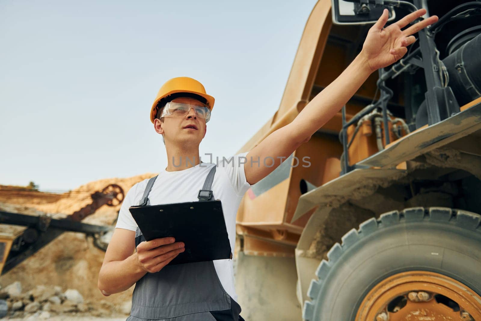 Manager planning the work. Man in professional uniform is on the borrow pit at daytime.