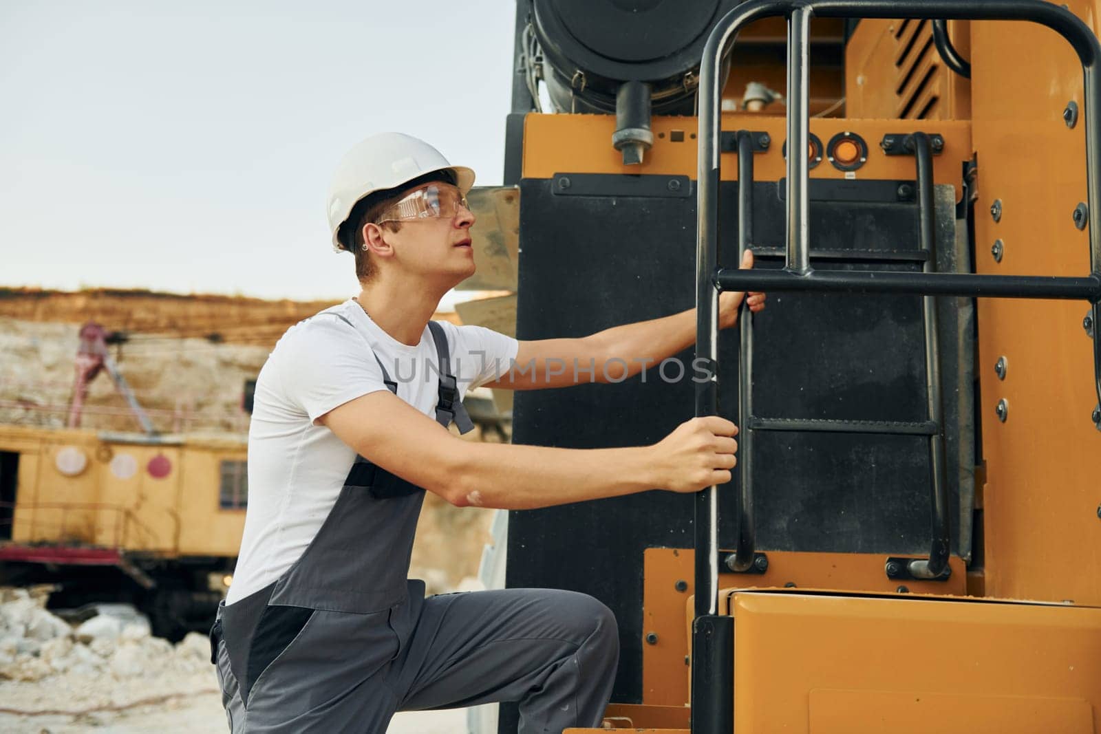 Quality vehicle. Worker in professional uniform is on the borrow pit at daytime.