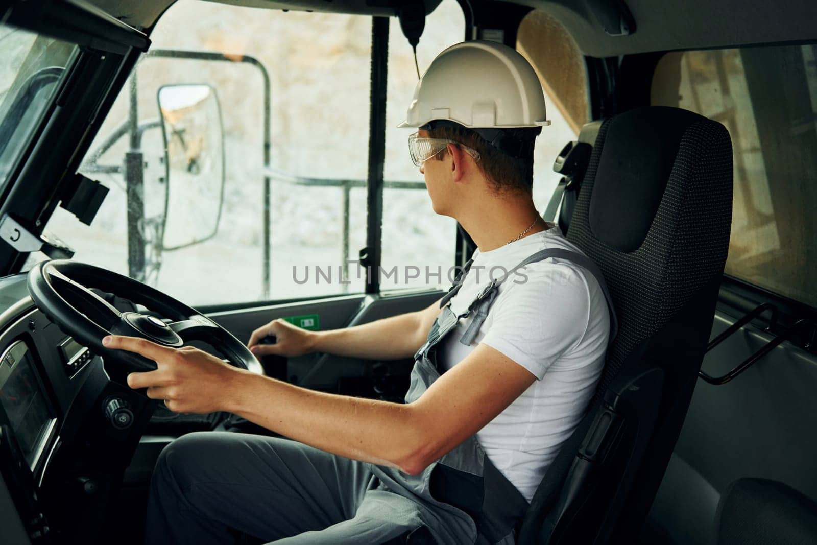 Driving transport. Worker in professional uniform is on the borrow pit at daytime.