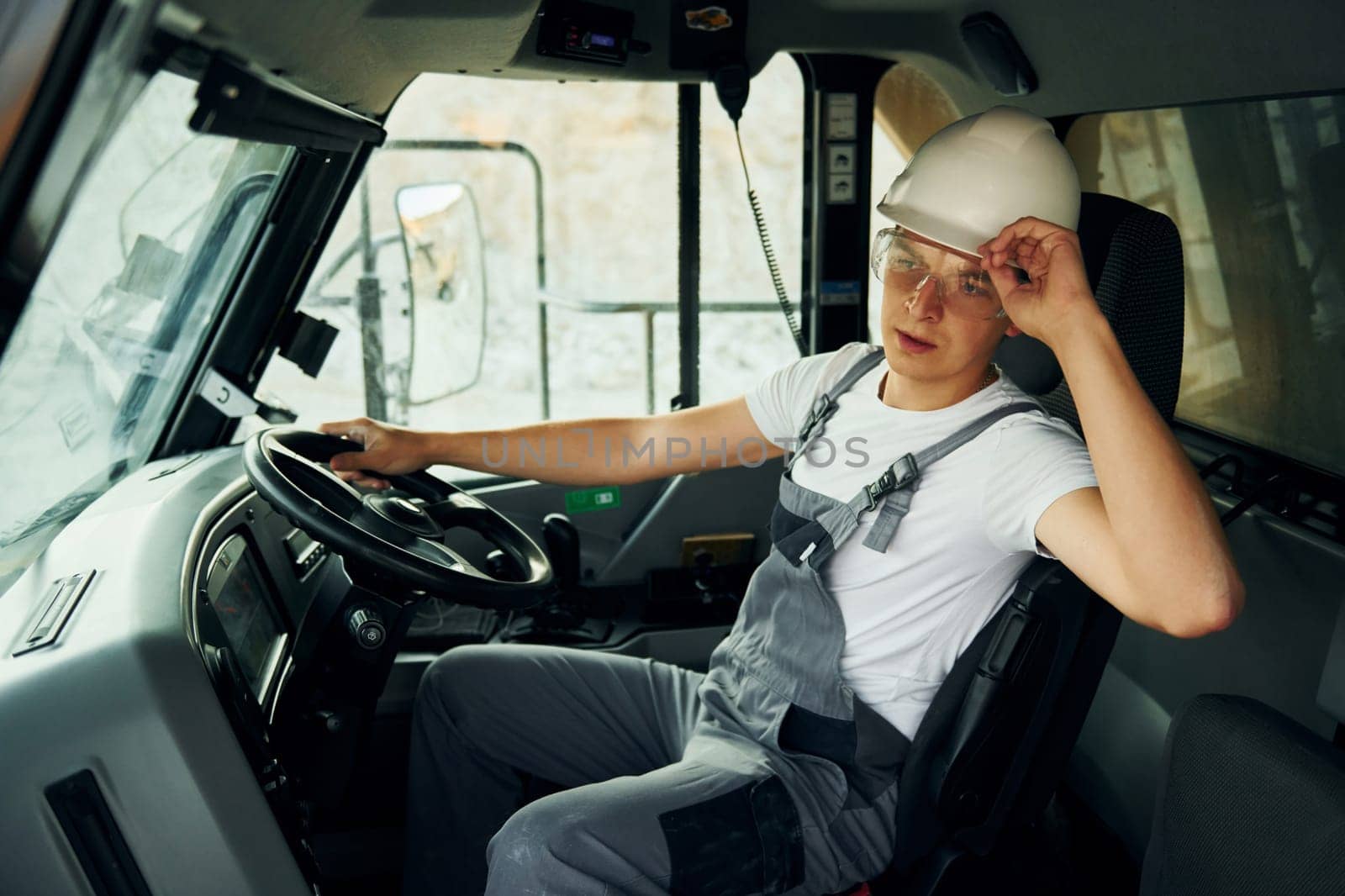Driving transport. Worker in professional uniform is on the borrow pit at daytime.