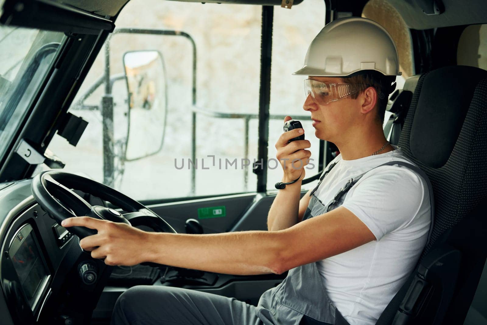 Driving transport. Worker in professional uniform is on the borrow pit at daytime.