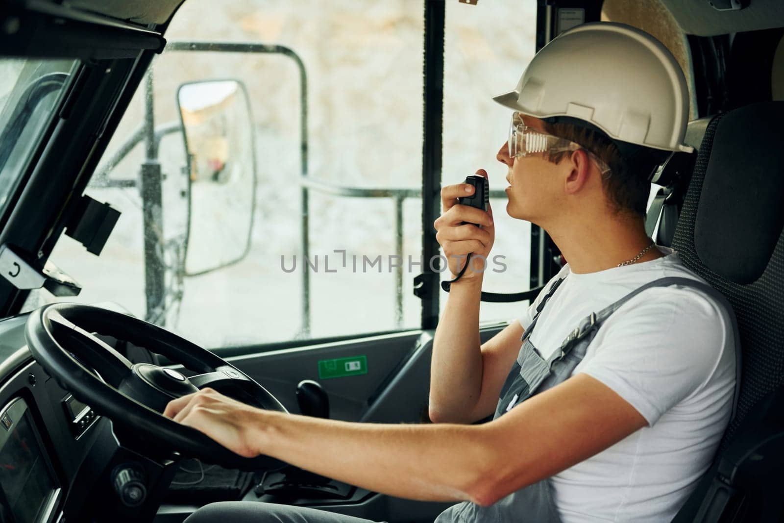Driving transport. Worker in professional uniform is on the borrow pit at daytime.