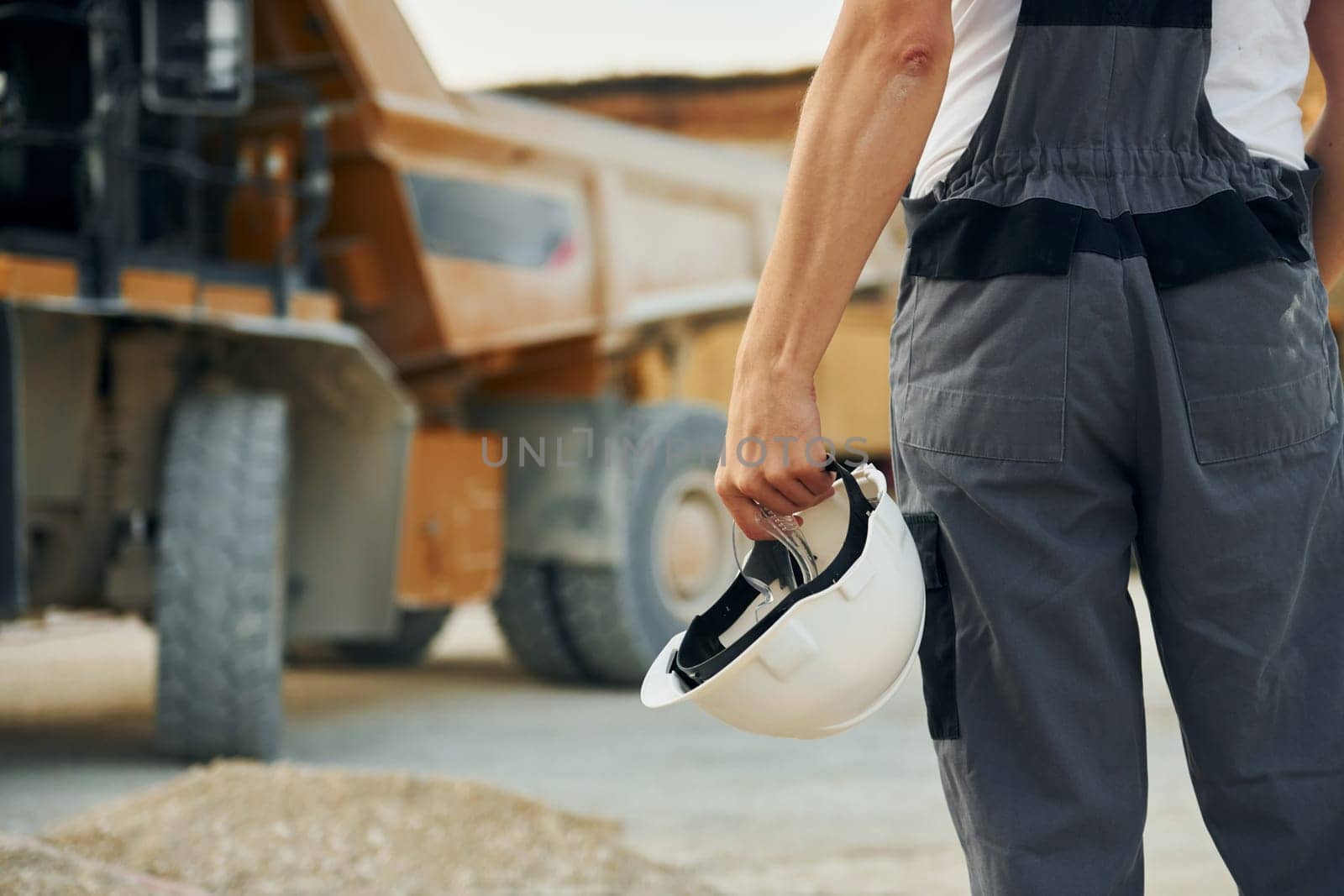 Close up view. Worker in professional uniform is on the borrow pit at daytime.