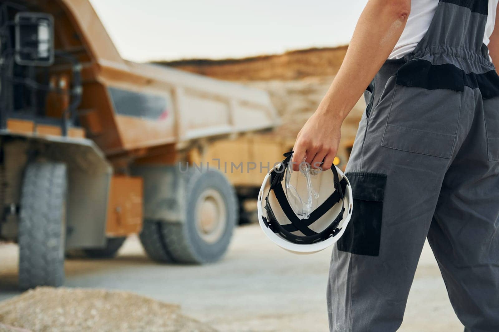 Close up view. Worker in professional uniform is on the borrow pit at daytime.